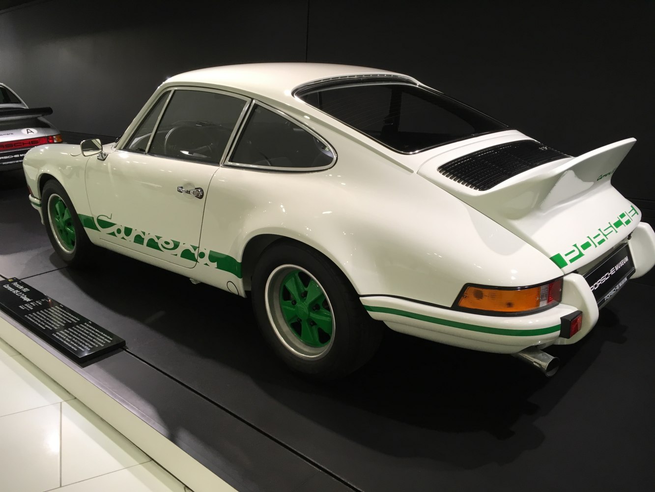 Rear side view of a classic coupe with ducktail spoiler and green-accented wheels