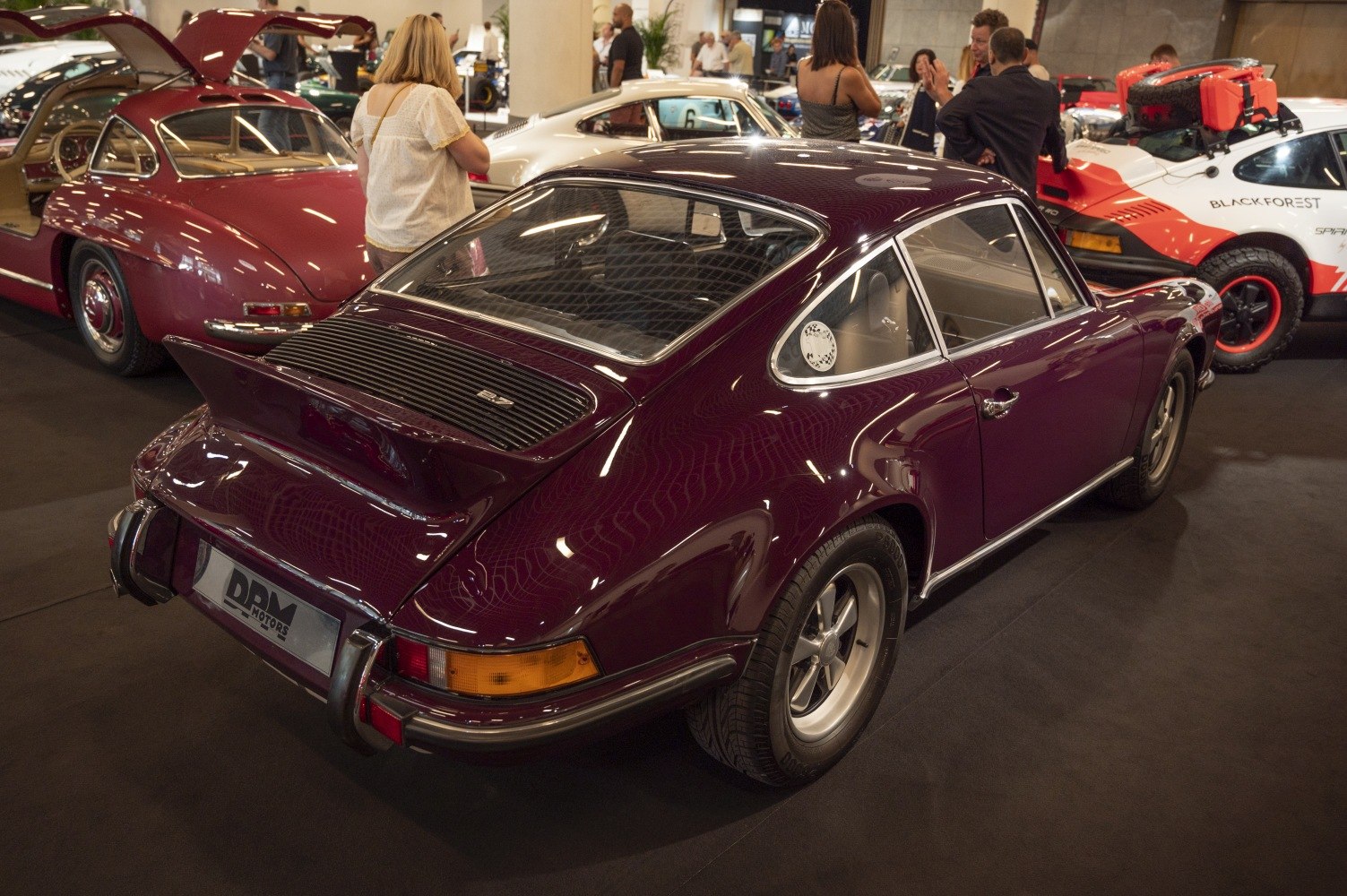 Rear side view of a classic sports coupe with a prominent rear spoiler and vintage five-spoke wheels.