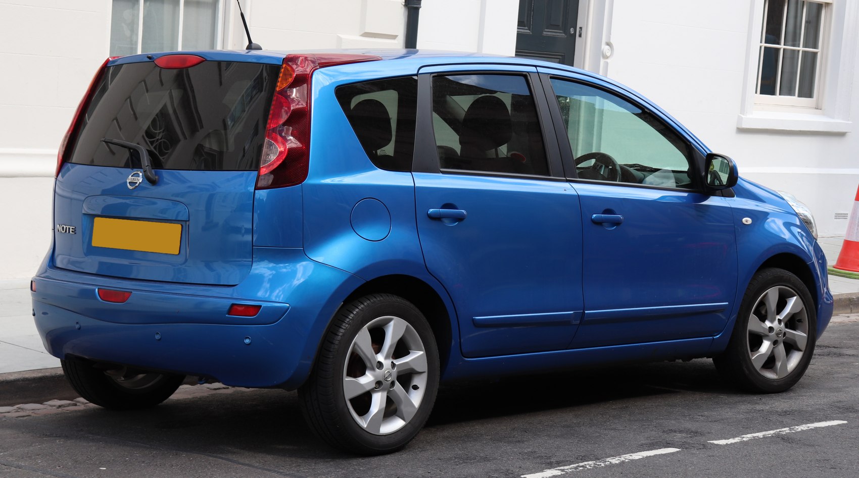 Rear side view of blue compact hatchback with vertical tail lights and alloy wheels