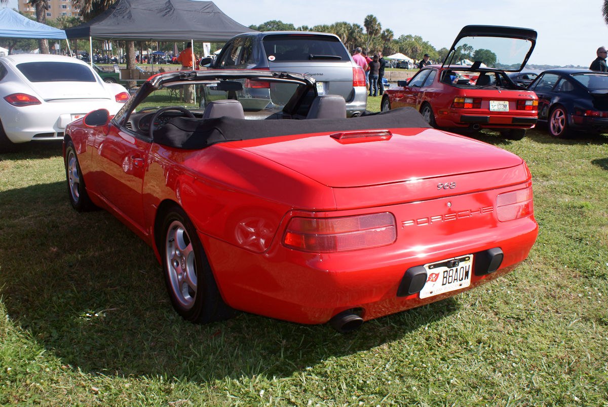 Rear view of a red convertible with black soft top and round taillights.