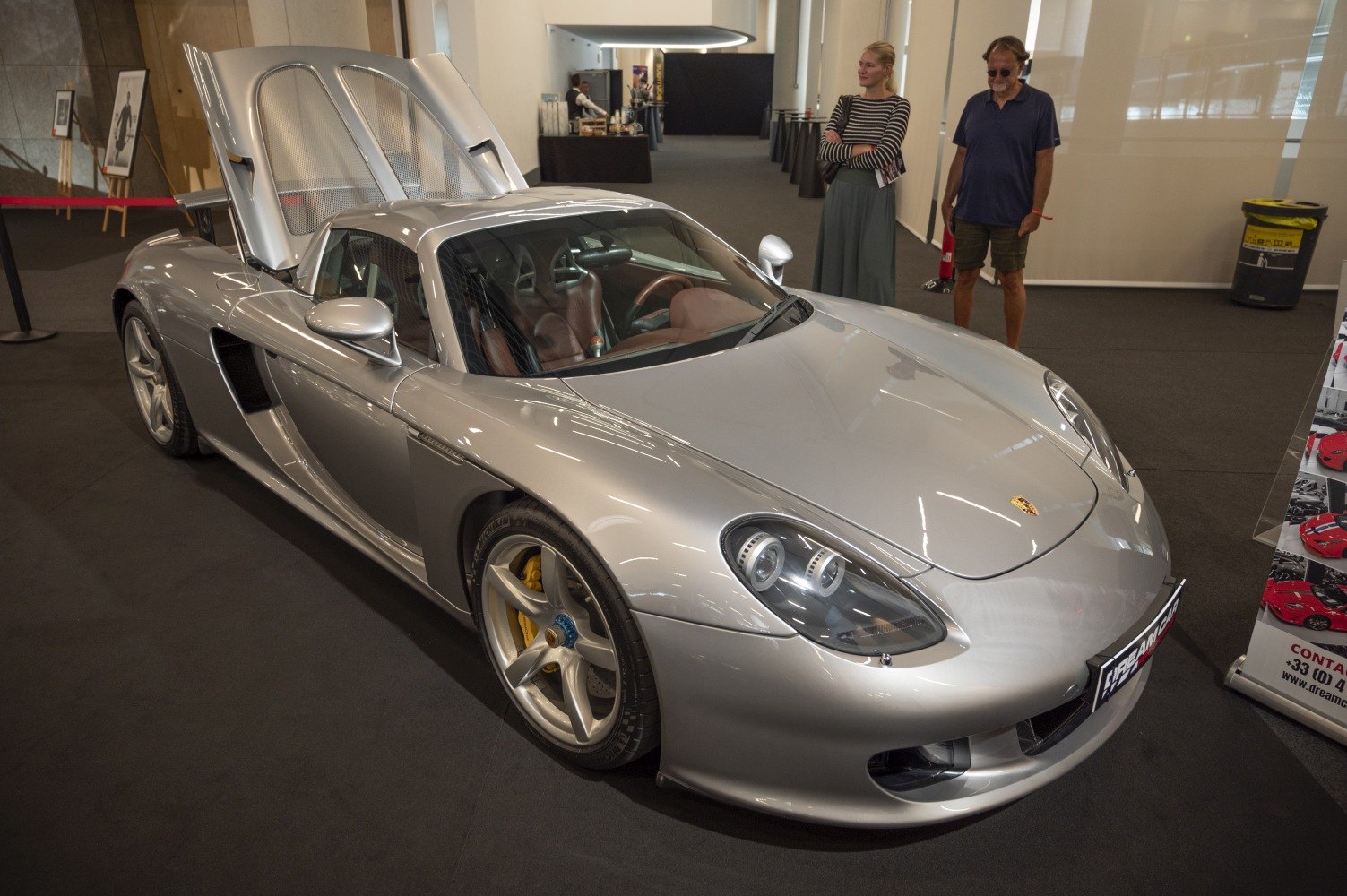 Silver mid-engine sports car with open rear hood and aerodynamic design