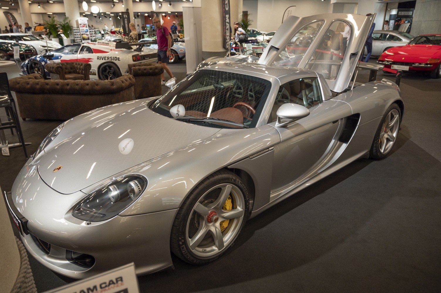 Silver mid-engine sports car with open rear hood and unique headlights