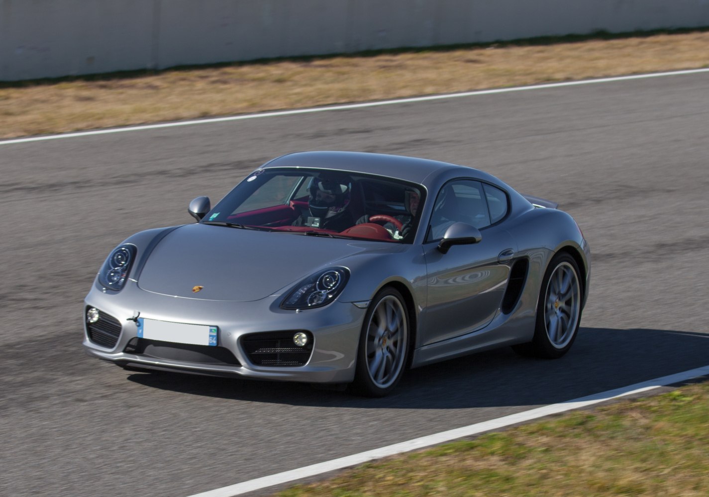 Dynamic front 3/4 view of silver sports coupe on track