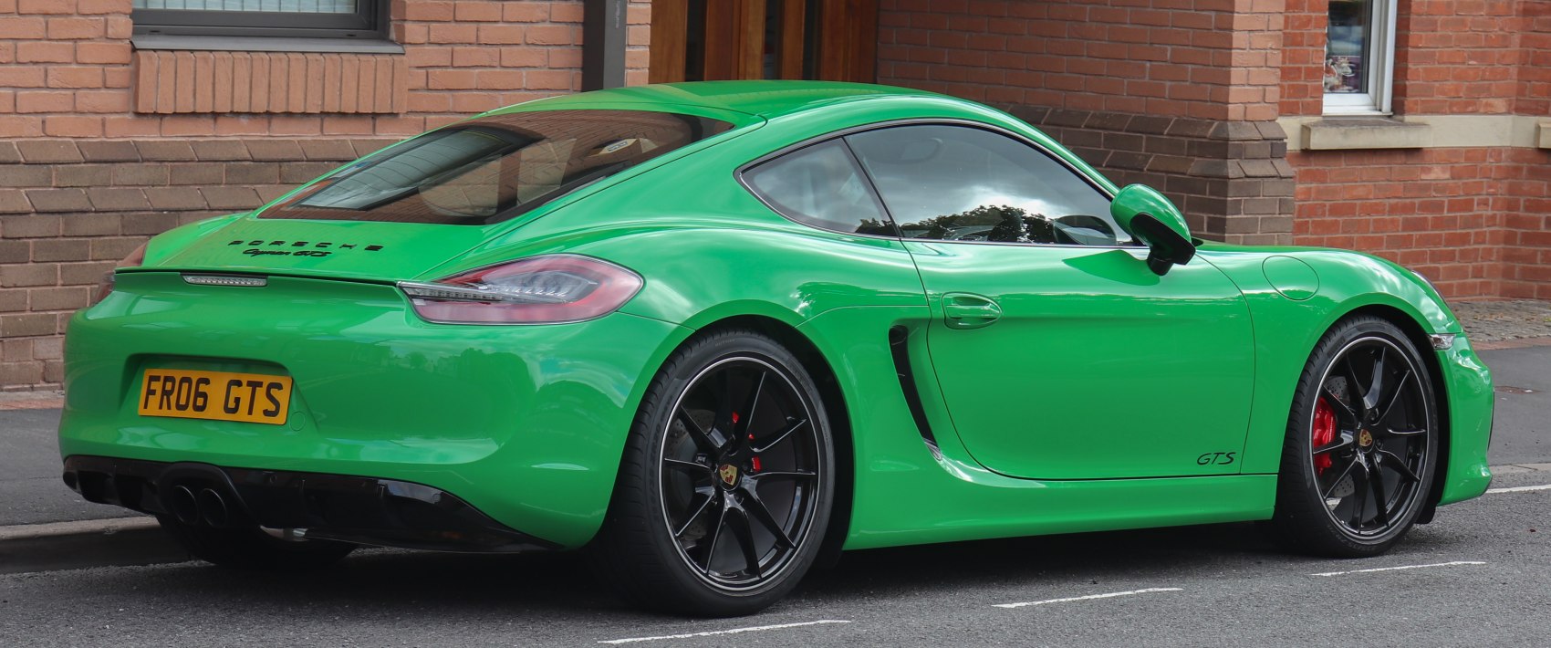 Rear side view of a green coupe with black alloy wheels and aerodynamic body lines