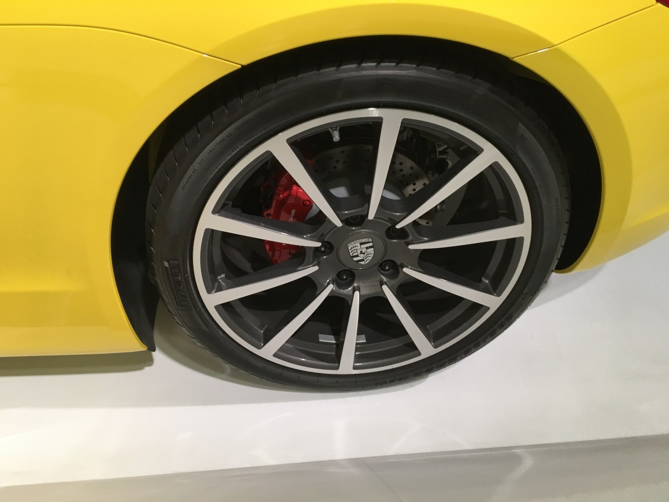 Alloy wheel with red brake caliper on yellow car body