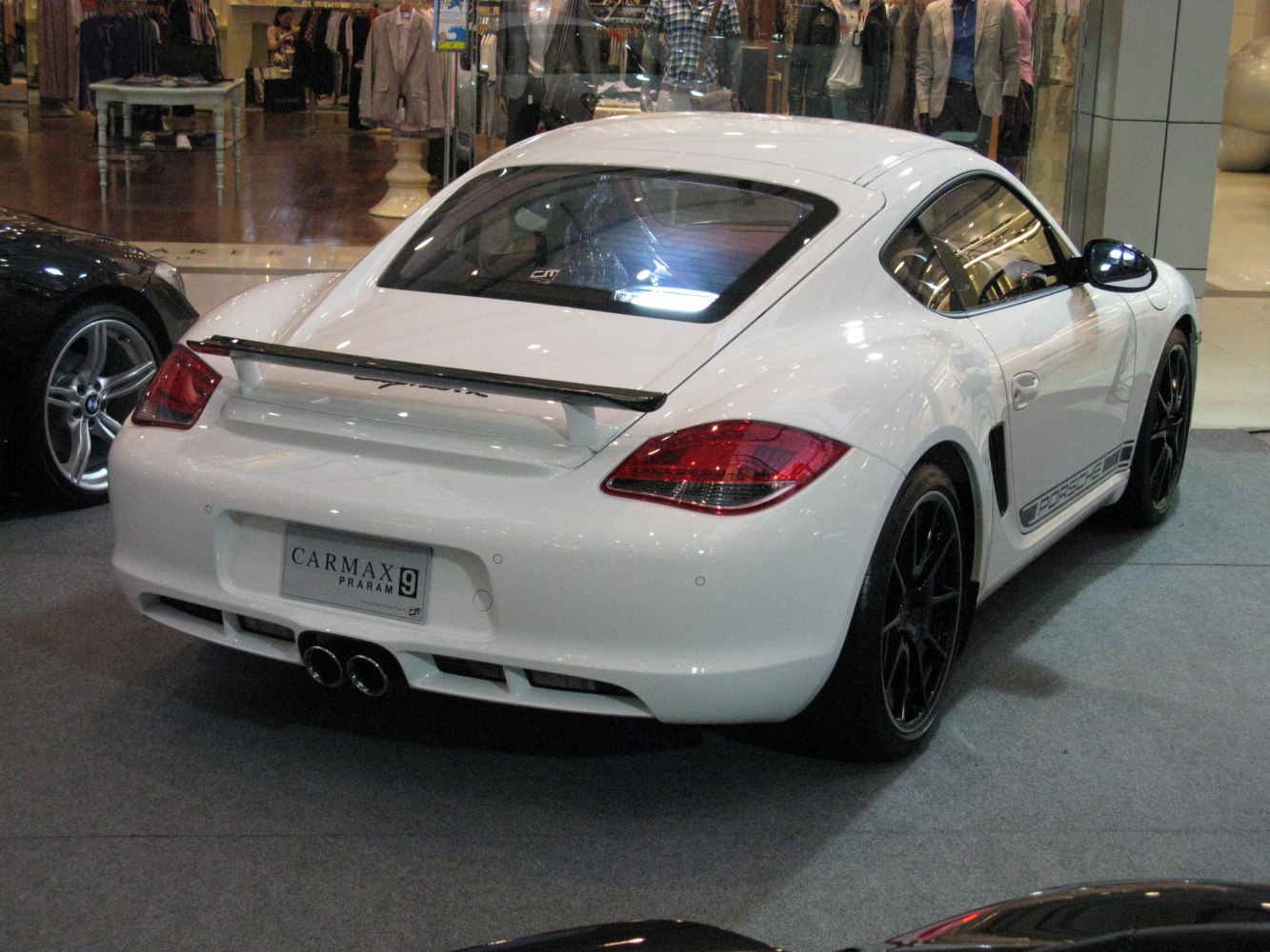 Rear and side view of white sports coupe with spoiler and black wheels