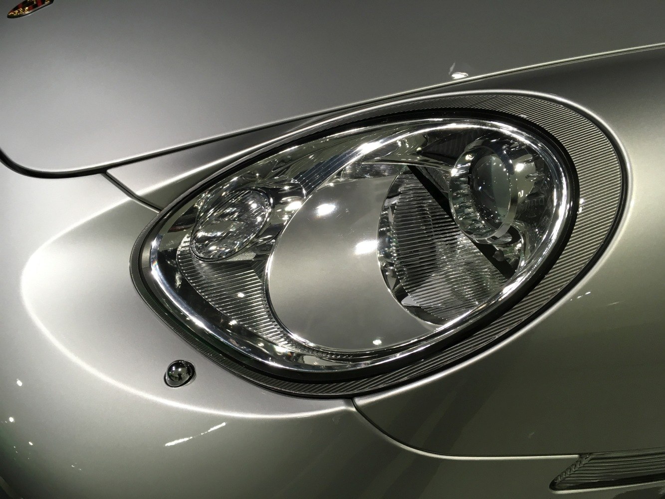 Close-up of a sleek, oval projector headlight with chrome and ribbed detailing