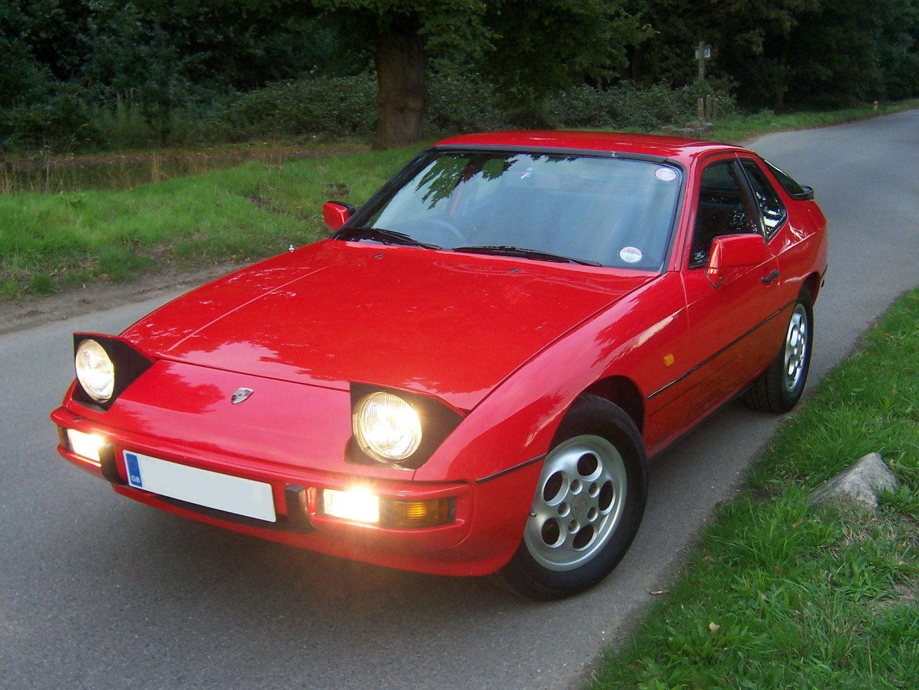 Classic red sports car with pop-up headlights and distinctive 5-spoke wheels
