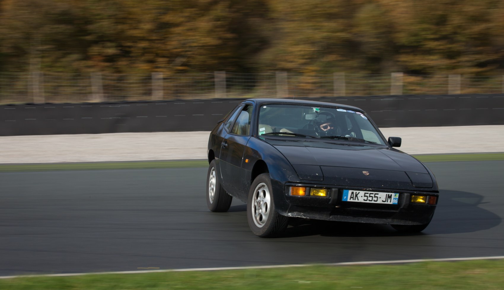 Black sports coupe with pop-up headlights drifting on track.