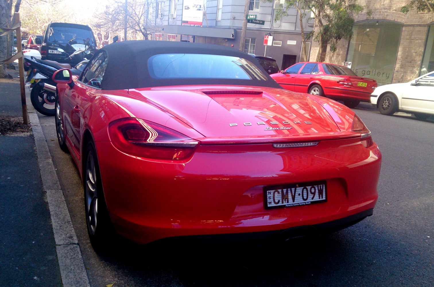 Red convertible sports car with black soft top and sleek rear design