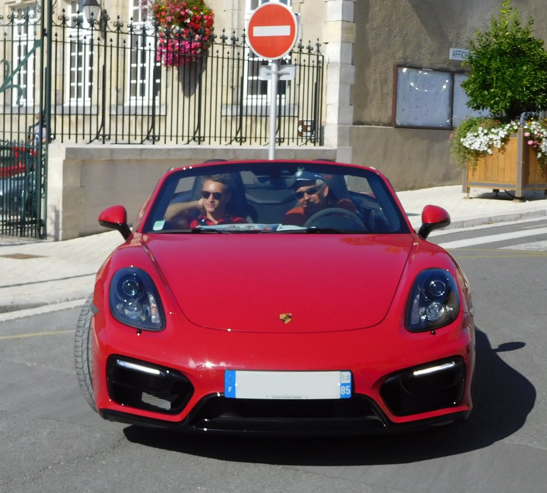 Front view of a red convertible sports car with two passengers