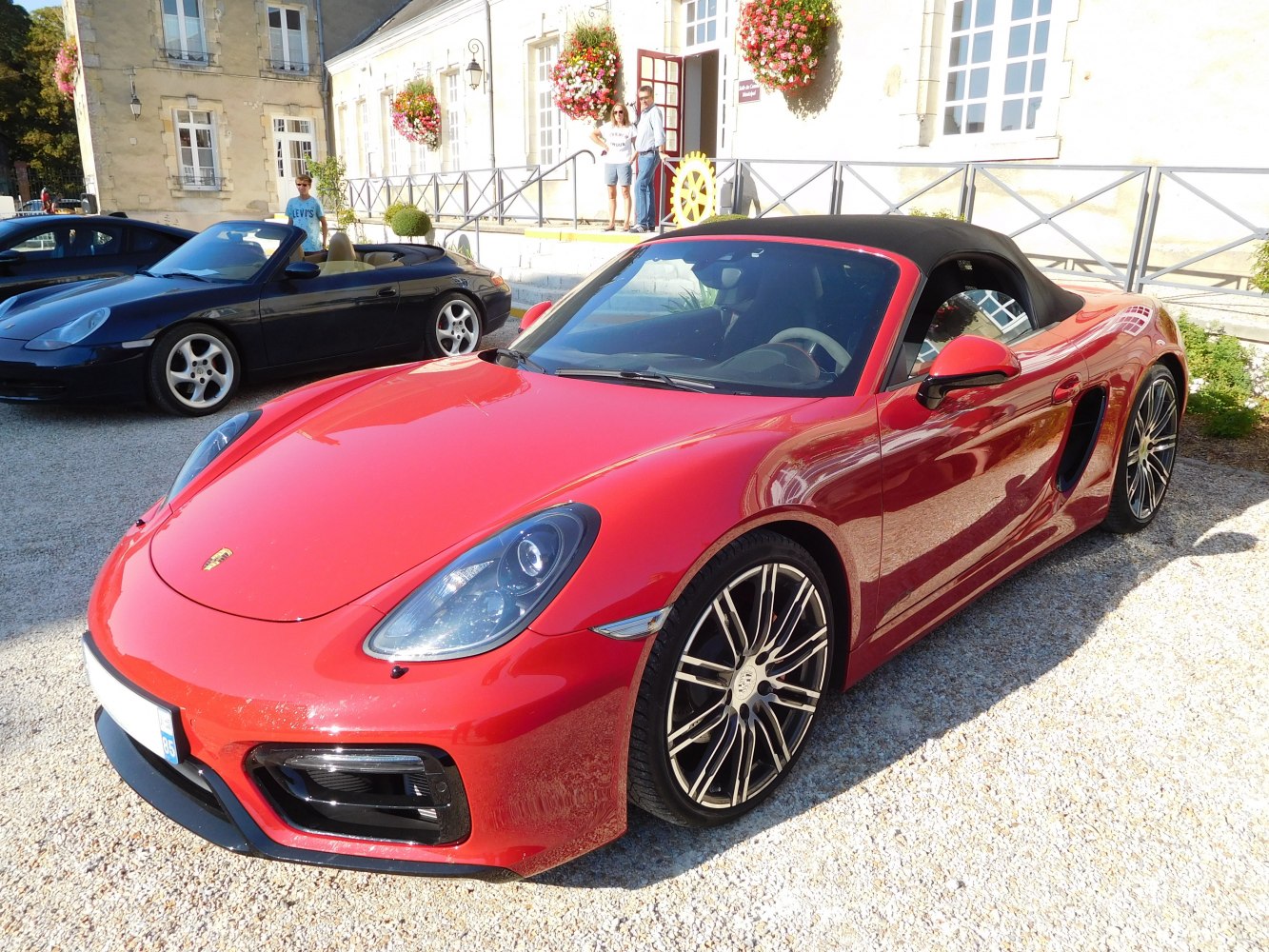 Red convertible sports car with black soft top and distinctive headlights