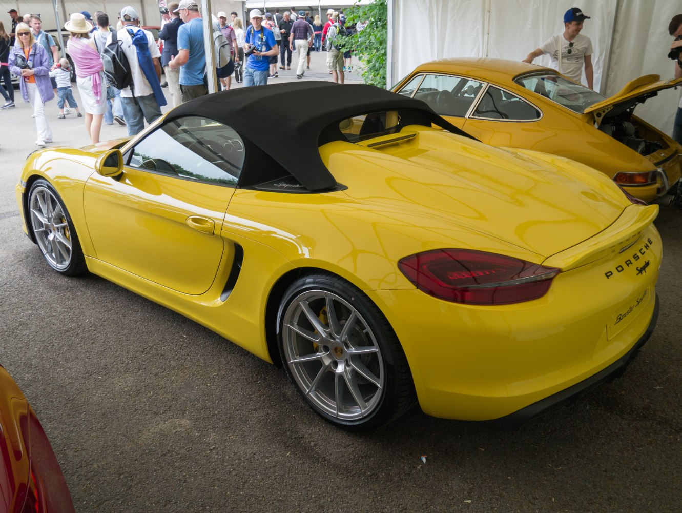 Yellow convertible sports car with black soft top and alloy wheels