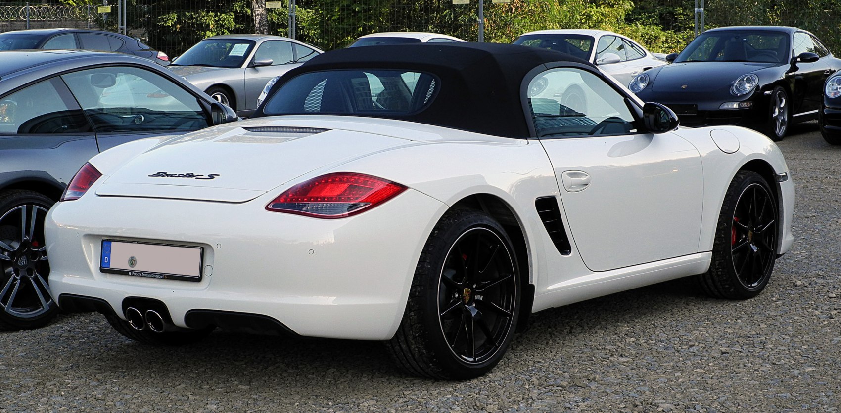 White convertible with black soft top and sporty black rims rear side view