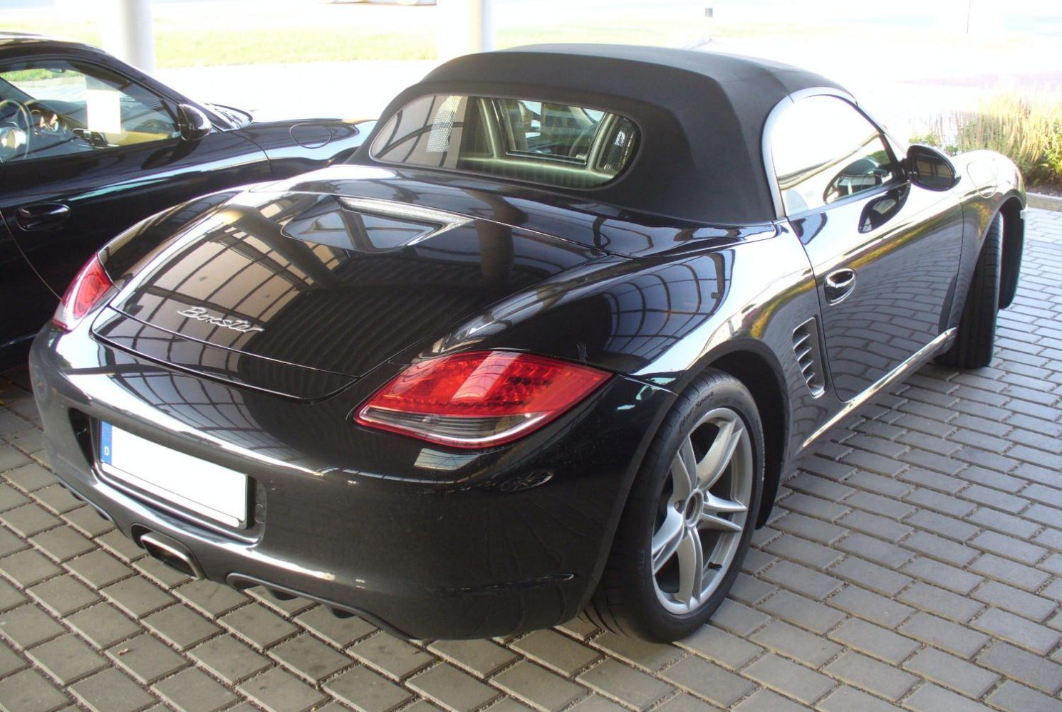 Convertible black roadster rear view with distinctive rear lights and alloy wheels