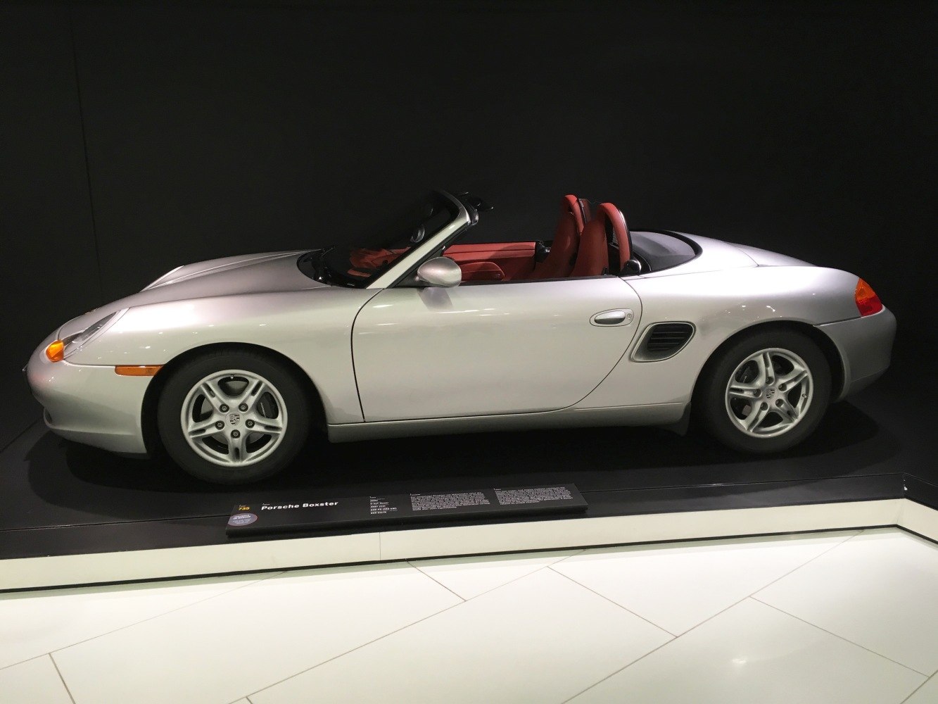 Silver convertible roadster with red leather interior and side air vents.