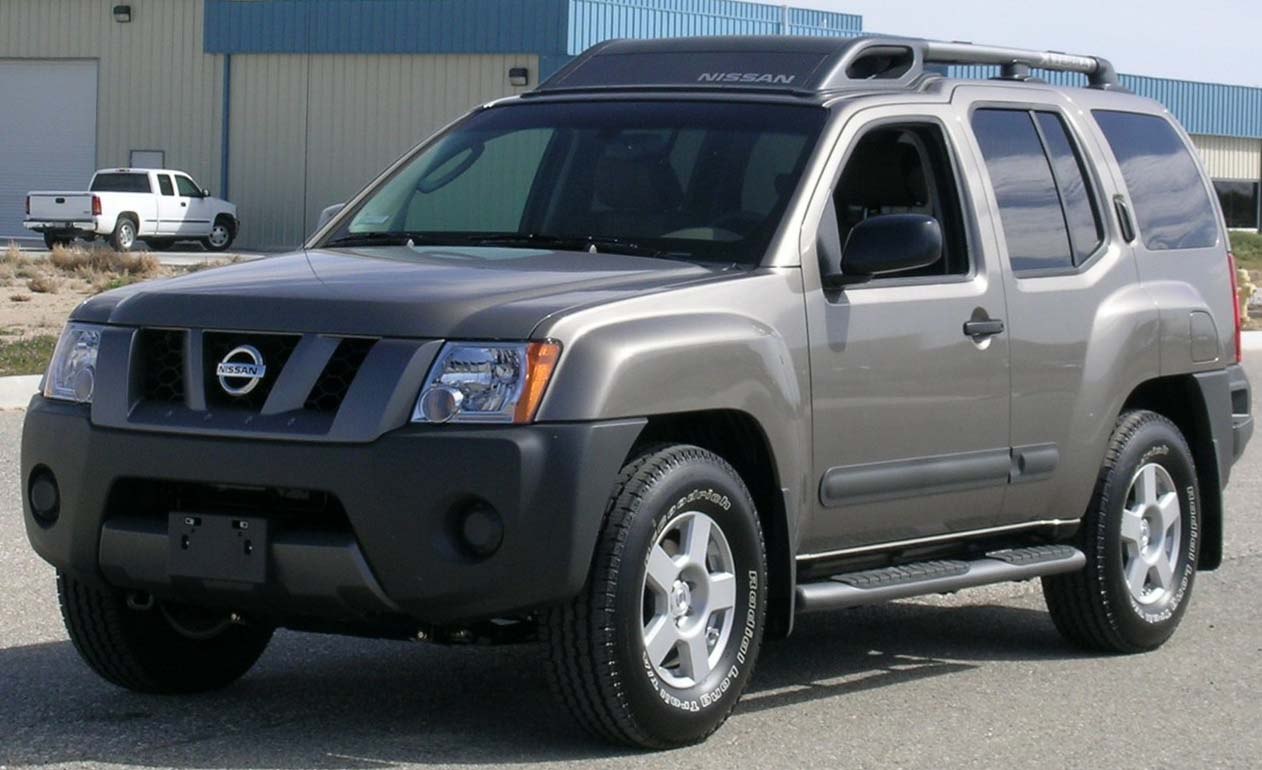 Front three-quarter view of a rugged SUV with roof cargo rack and side steps.