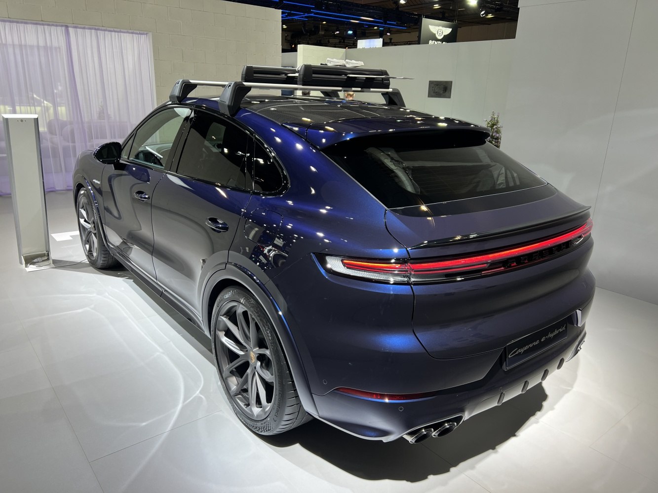 Rear-side view with quad exhaust and roof rack on sleek SUV coupe.