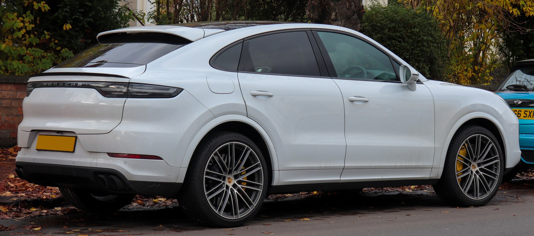 Rear and side view of white luxury SUV with sporty rear spoiler and alloy wheels