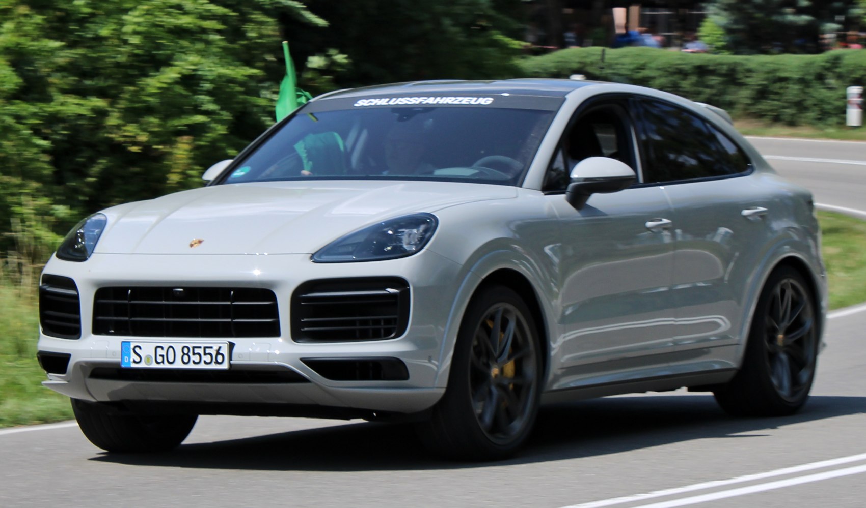 White Porsche SUV front view on road