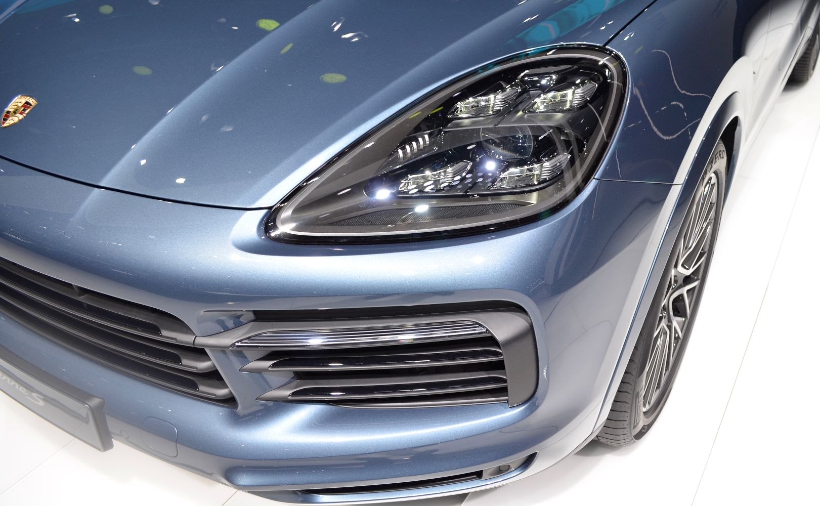 Close-up of LED headlight and front grille design on blue SUV