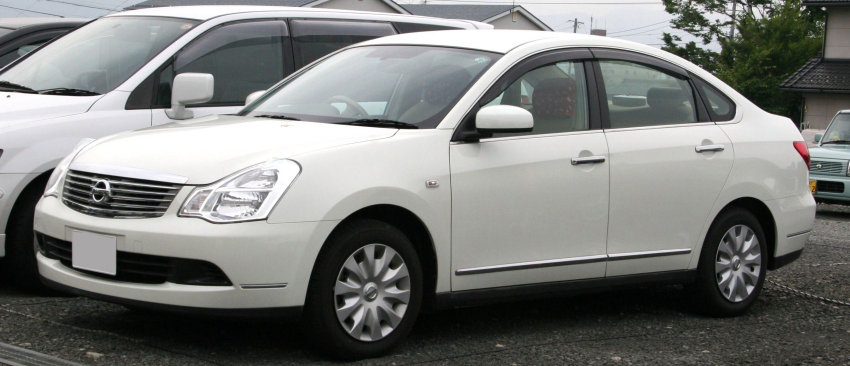 Side profile of a white mid-size sedan with distinctive headlights and wheel covers