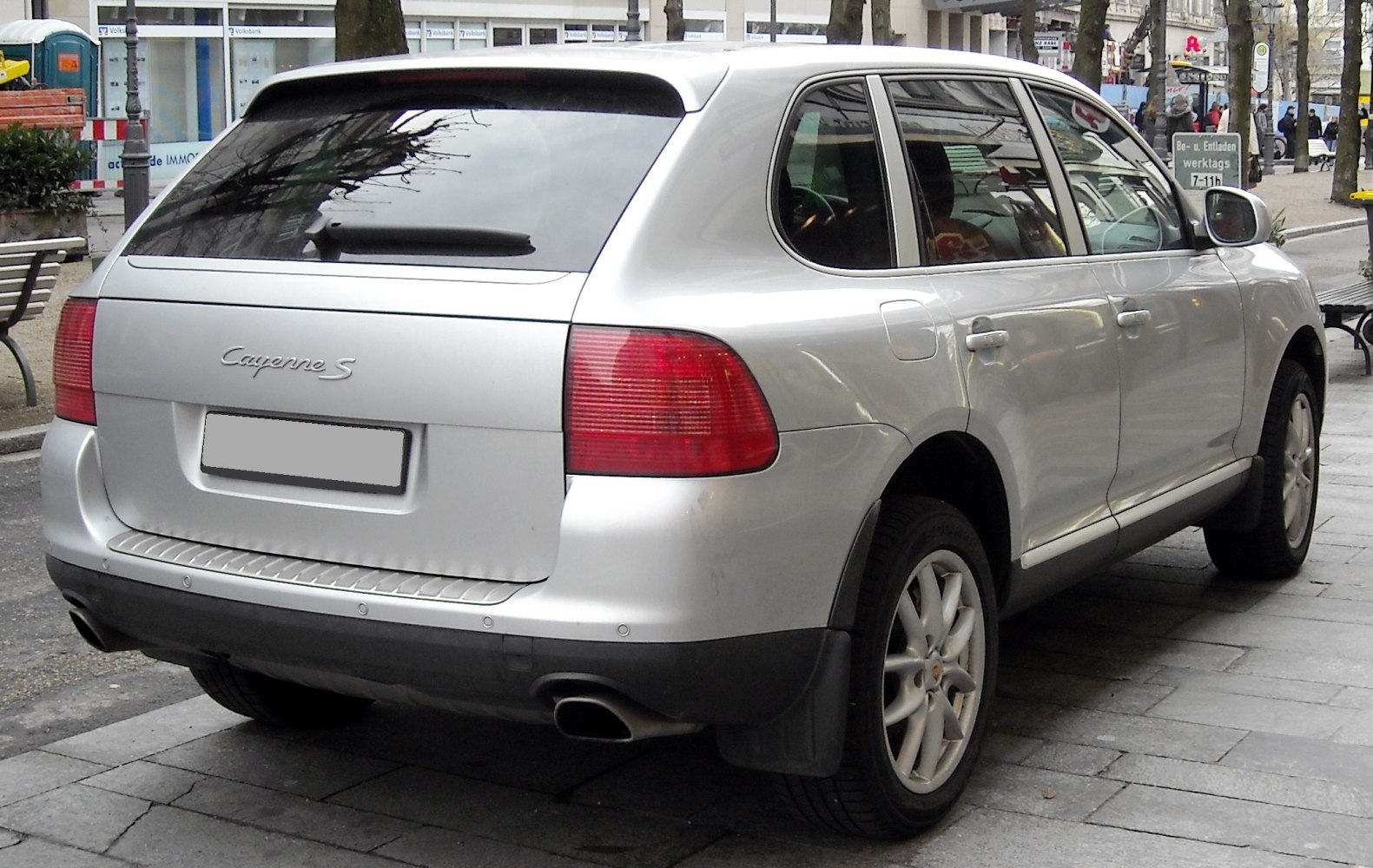 Silver SUV rear view with red tail lights and dual exhaust