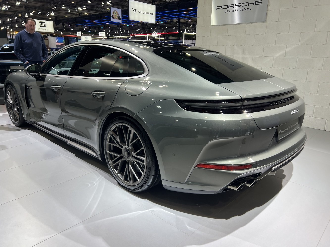 Luxury sedan rear with sleek lights, quad exhaust, and large alloy wheels.