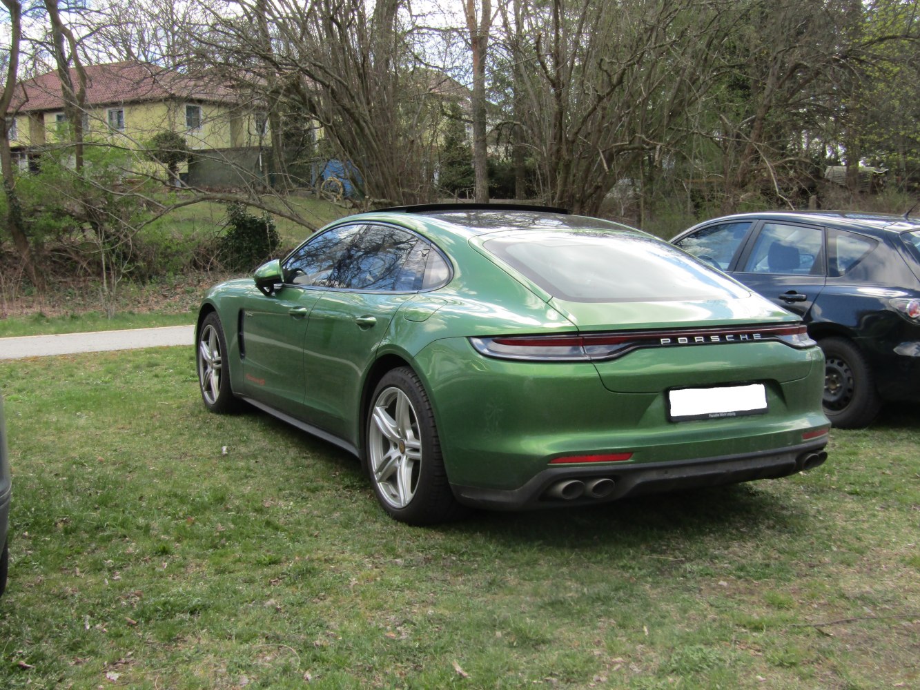 Sleek rear and side view of green luxury sports sedan with quad exhaust and panoramic roof