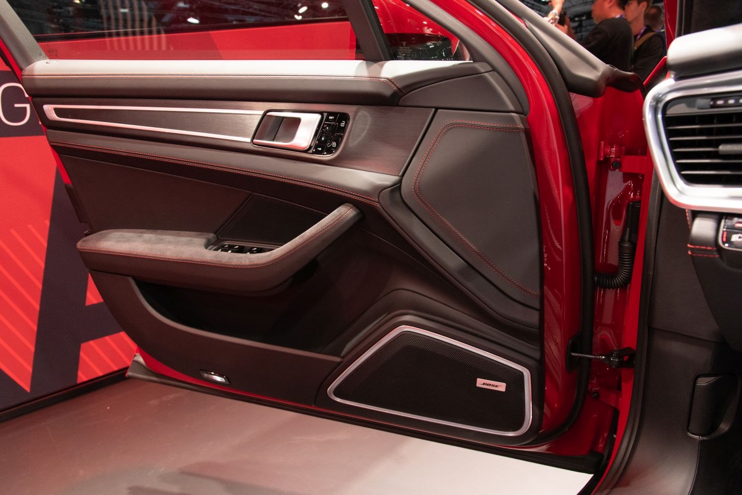 Luxury car door panel with red stitching and Bose speaker