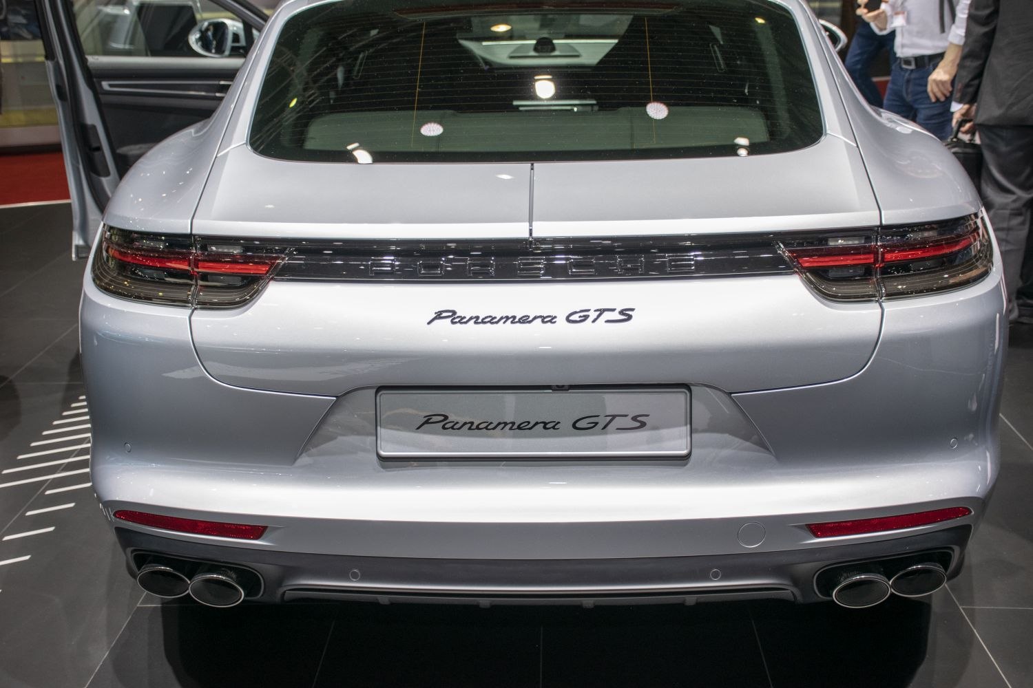 Rear view of a luxury sedan with connected taillights and quad exhaust pipes