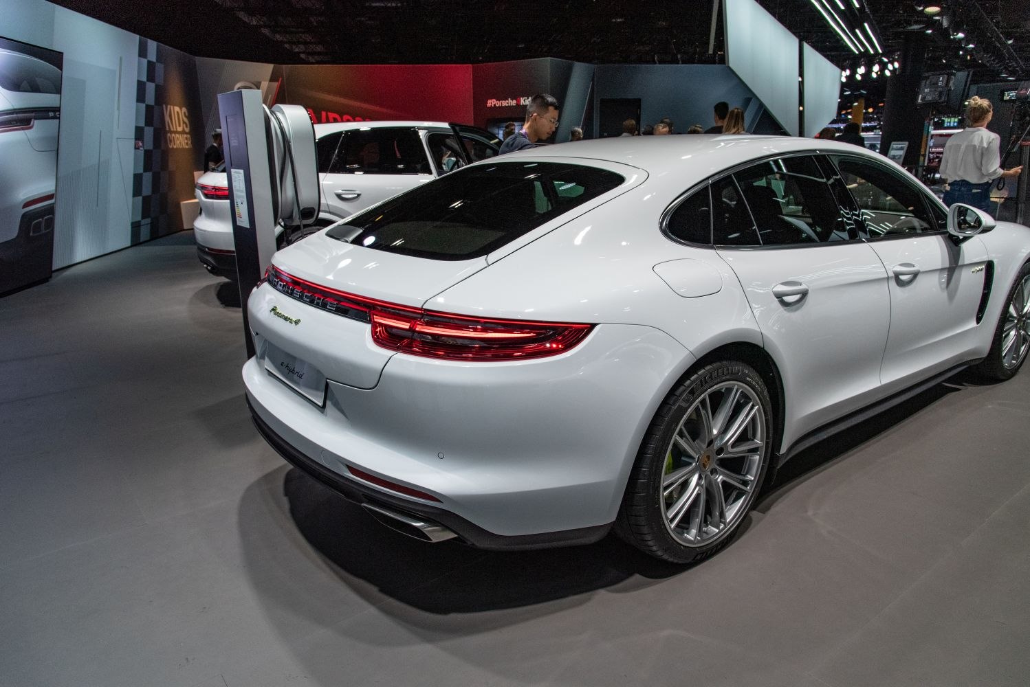 Rear view of luxury white sedan connected to charging station