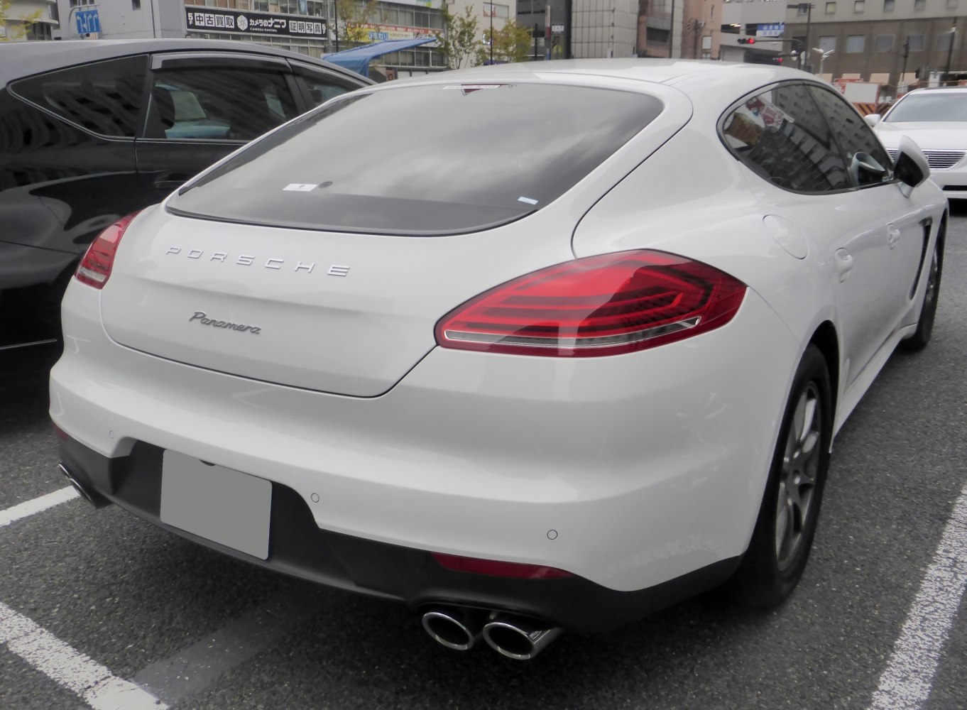 Rear of a white luxury sports sedan with quad exhaust and distinctive tail lights