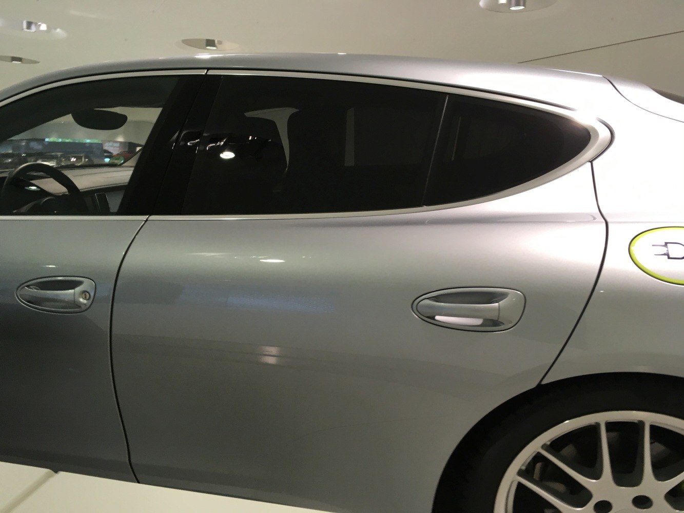 Silver car side profile with rear door, window, and charging port