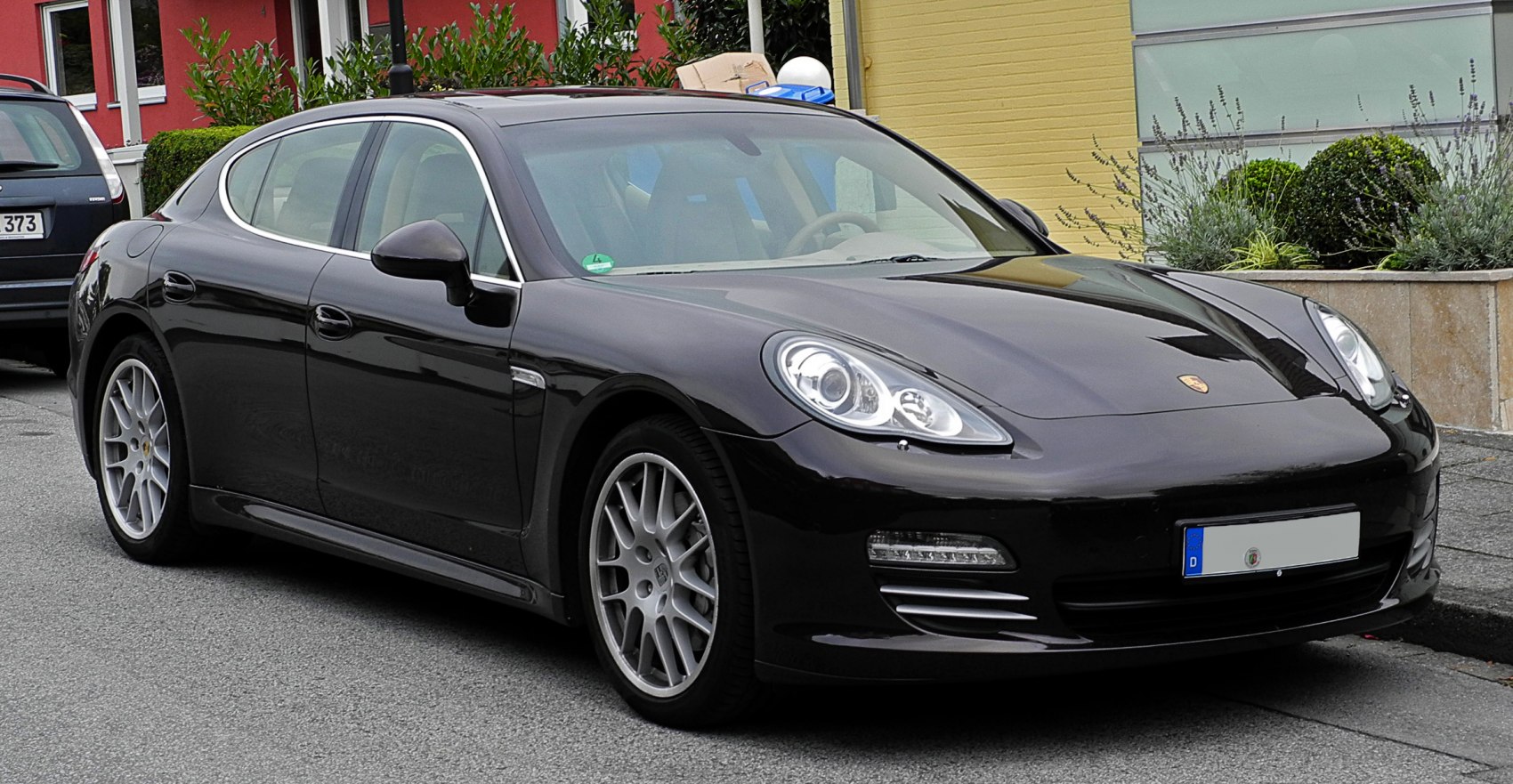 Black luxury four-door sedan with oval headlights and alloy wheels