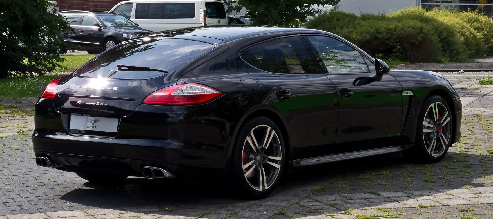 Rear three-quarter view of sleek black luxury sedan with quad exhausts and tinted windows