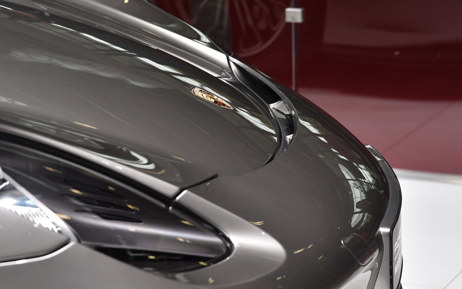 Close-up of front hood and badge with sleek curves and air intake.
