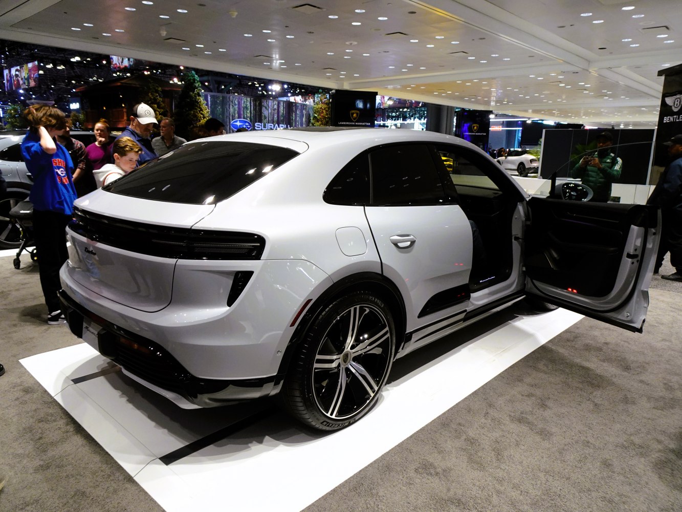 Rear view of white electric SUV with open door and glossy black rims