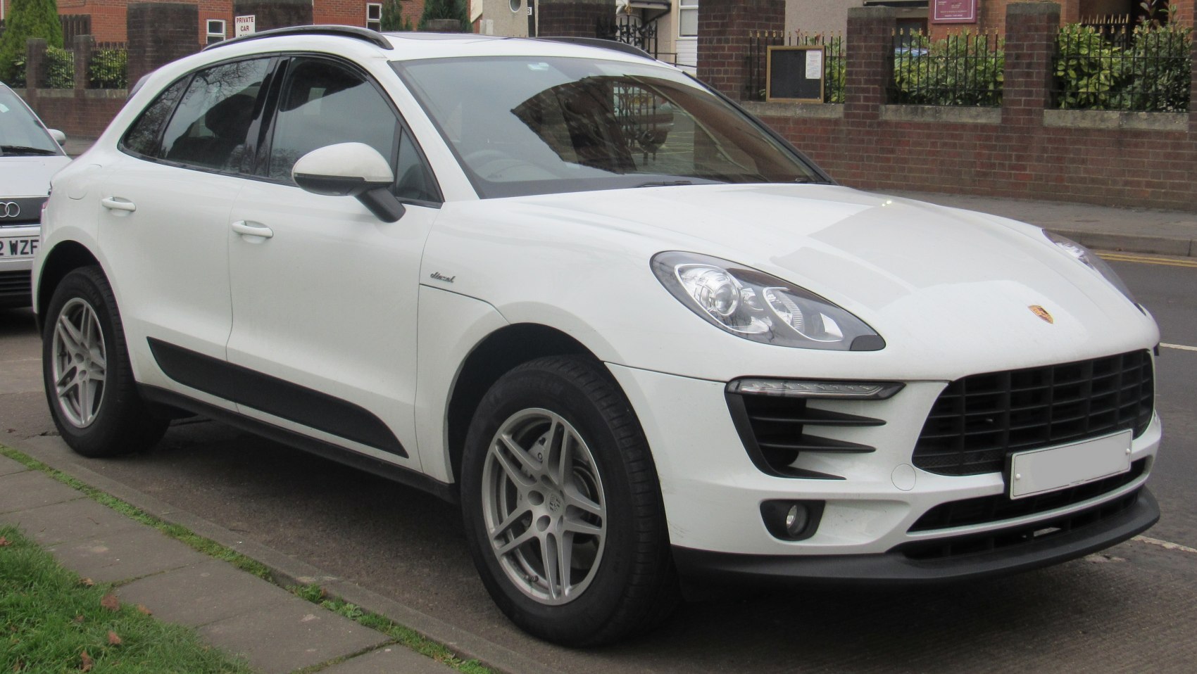 Front side view of a white luxury SUV with prominent headlights and sleek styling