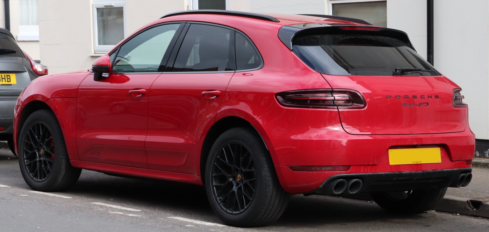 Rear-side of a sporty red SUV with black rims and quad exhaust pipes