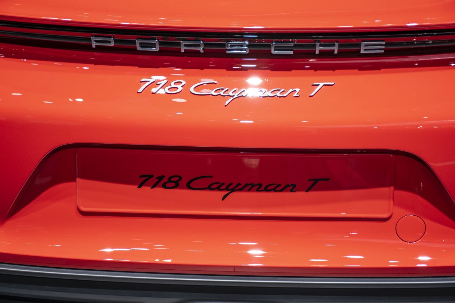 Close-up of rear badge and Porsche lettering on orange car