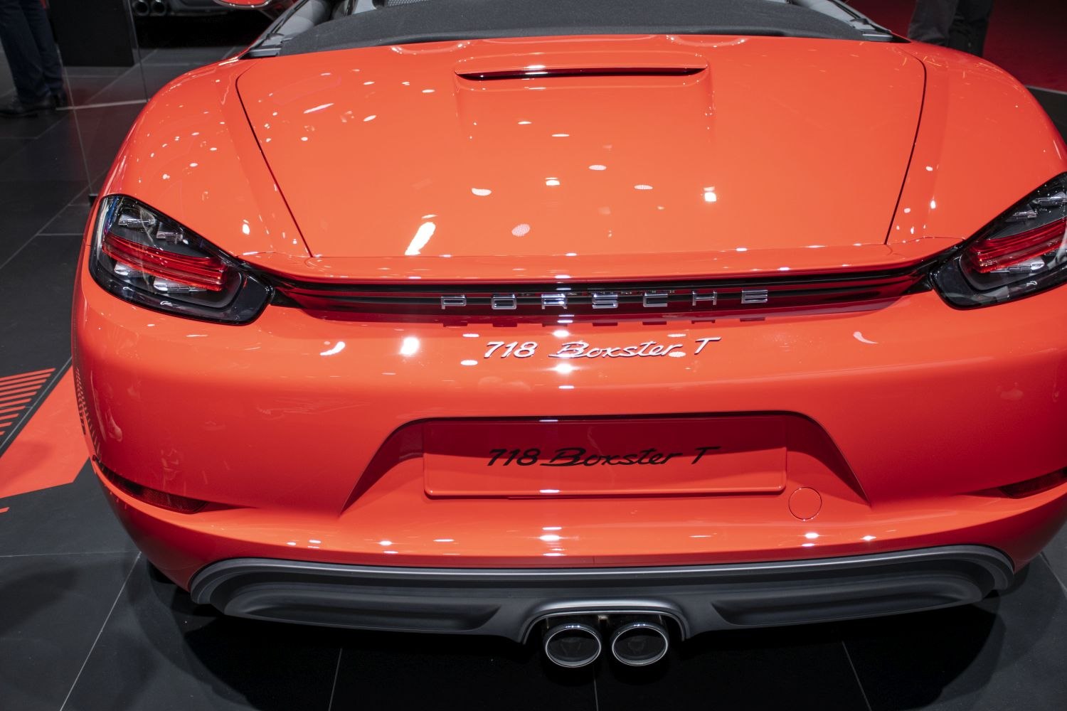 Rear of bright orange sports car with dual exhaust and sleek taillights