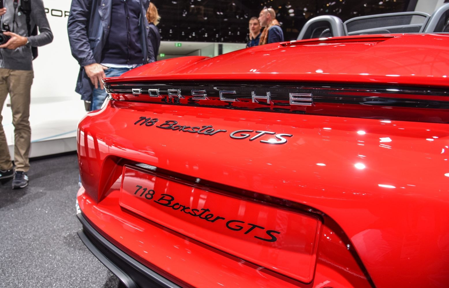 Close-up of rear Porsche emblem and 718 Boxster GTS badge on red sports convertible
