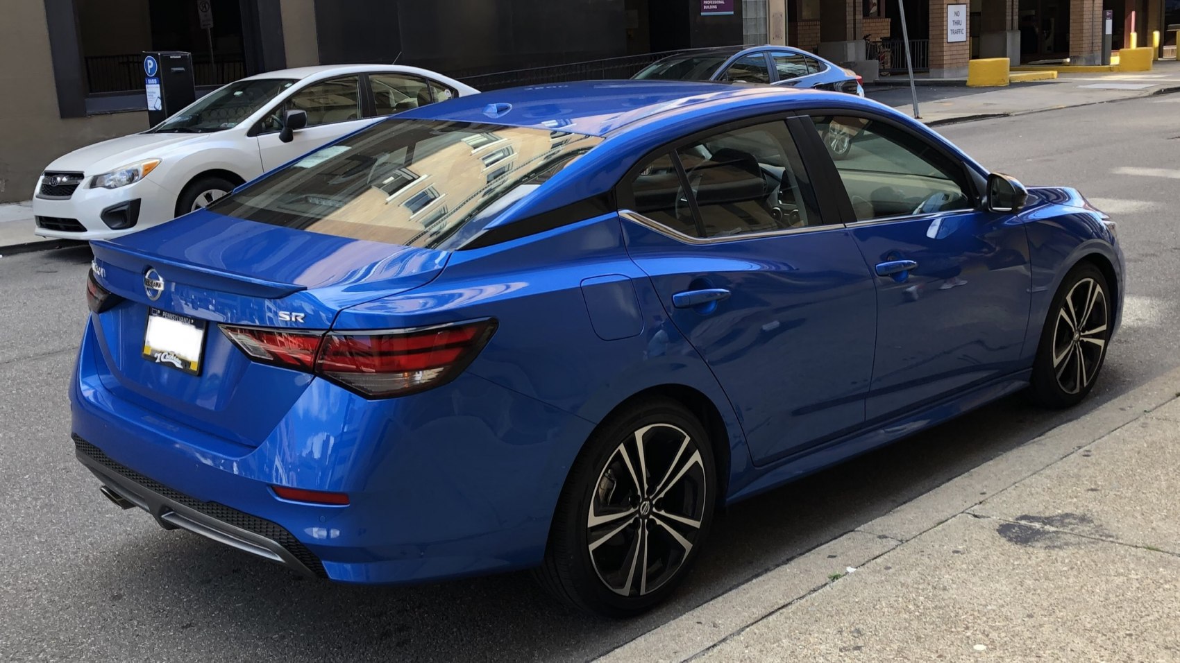 Rear-side view of blue sedan with modern taillights and sporty wheels