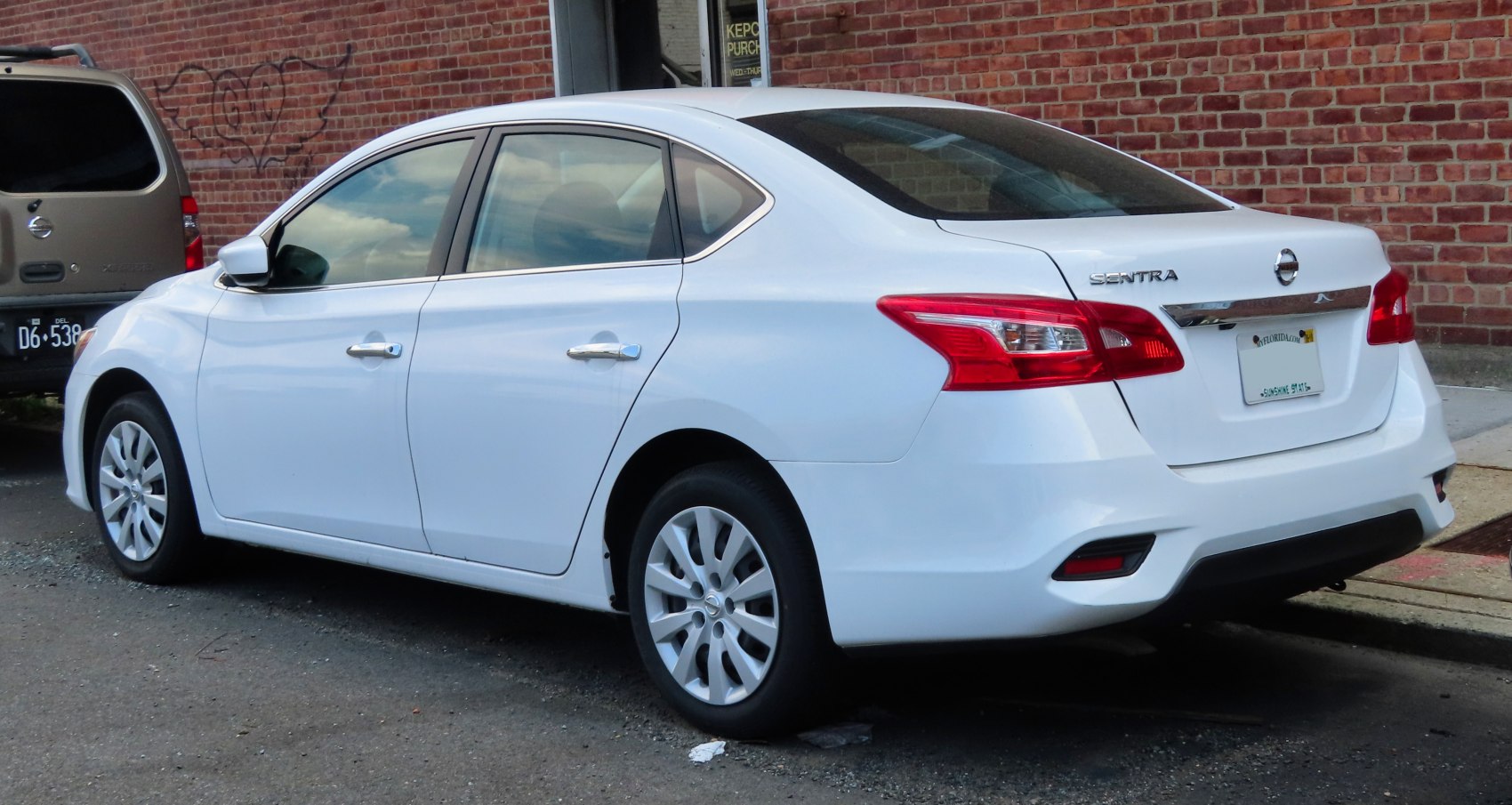 White sedan rear side with tail lights and chrome trim