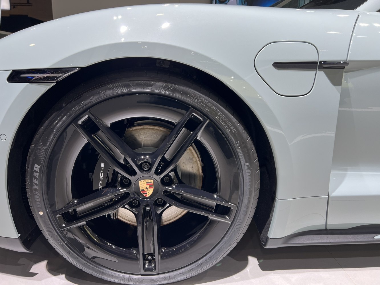 Black alloy wheel and side detail with charging port on light-colored vehicle
