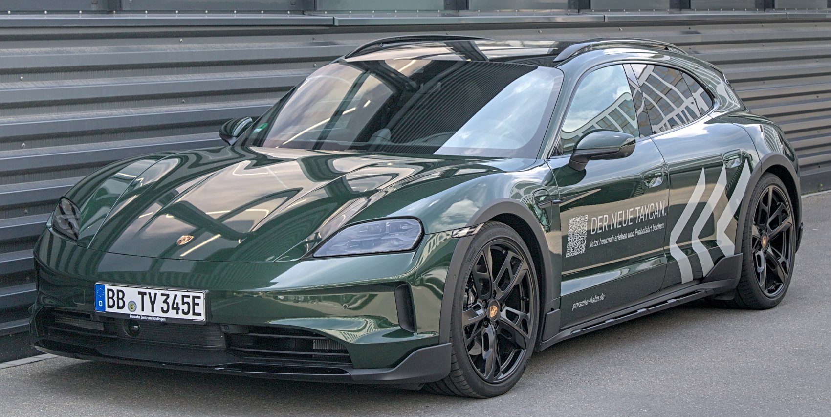 Electric sports wagon with aerodynamic front, black rims, roof rails, and side decals