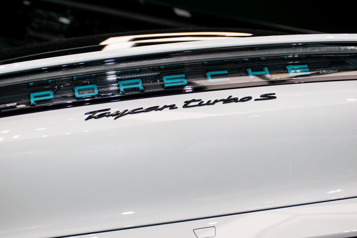Close-up of rear badge and LED light strip on white luxury vehicle