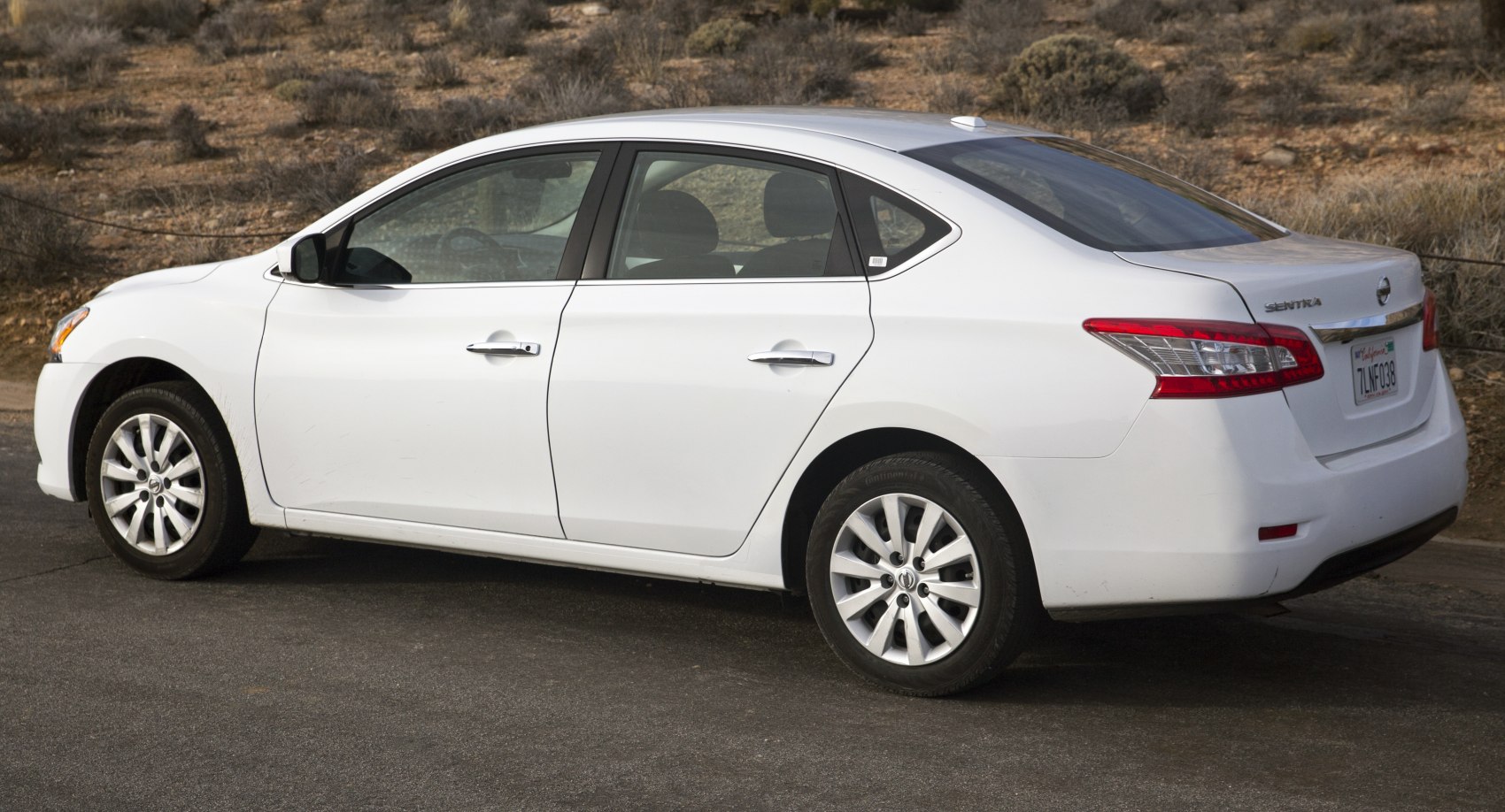 White four-door sedan rear side with alloy wheels and rear lights