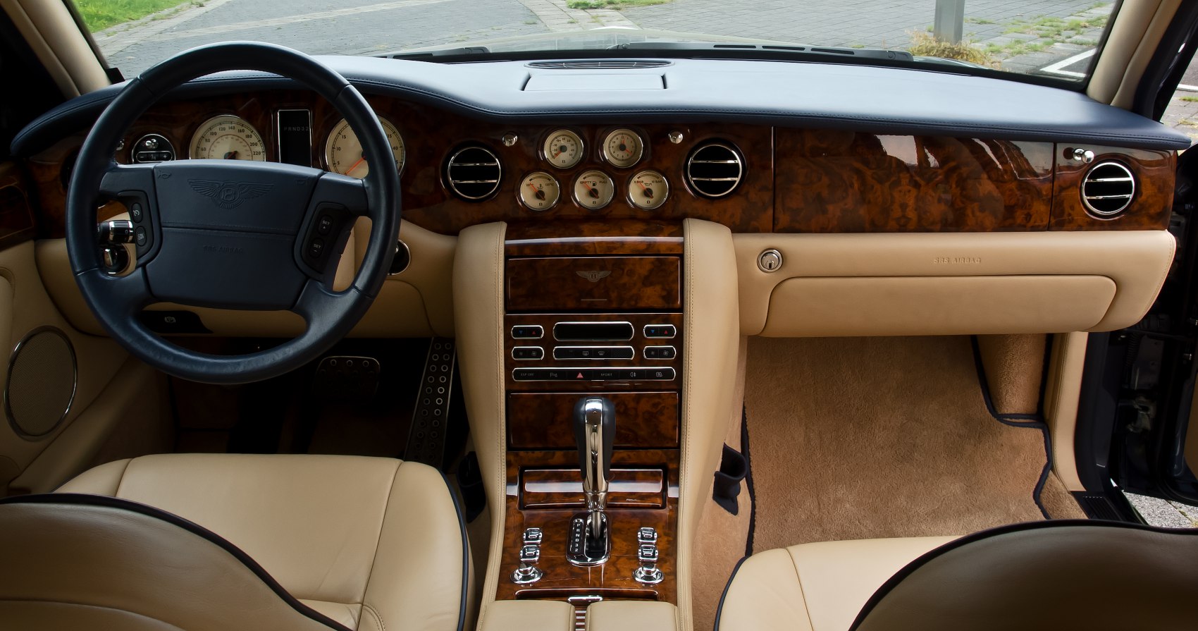Classic wood-trimmed dashboard and beige leather interior with gauges and controls